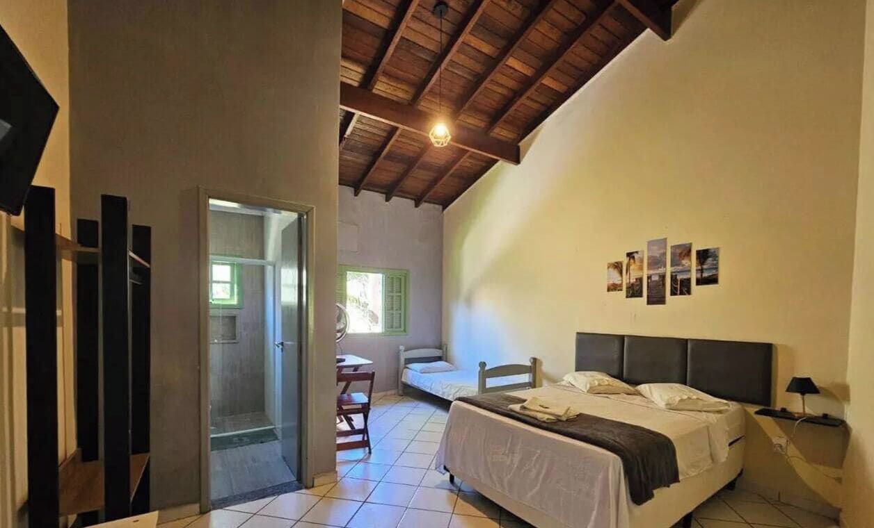 Ein Schlafzimmer mit einem Bett, einem Nachttisch, einem Fenster und einer Tür zu einem anderen Raum.