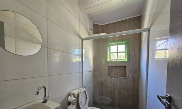 Un baño con inodoro, lavamanos y zona de ducha.