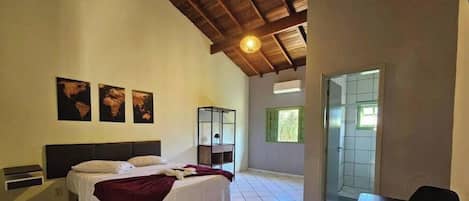 Un dormitorio con cama, mesita de noche, escritorio y ventana.