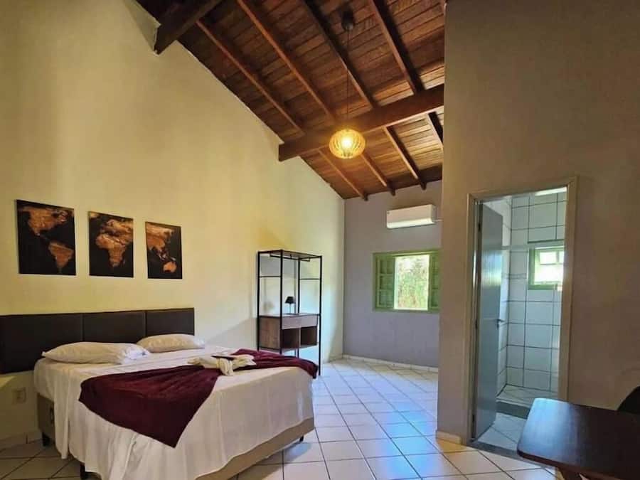 Un dormitorio con cama, mesita de noche, escritorio y ventana.