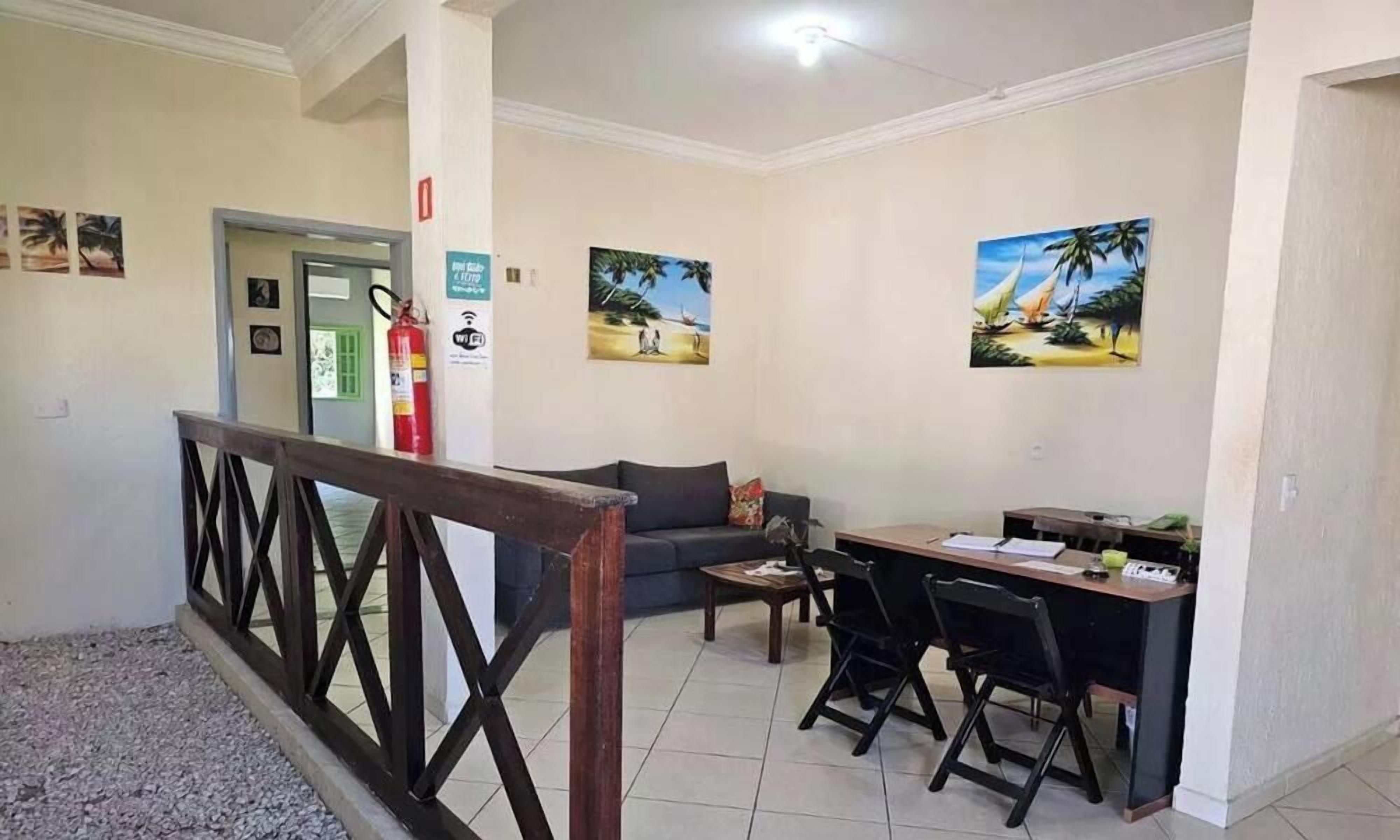Un vestíbulo de hotel con una recepción, un sofá, una mesita de café y un extintor.