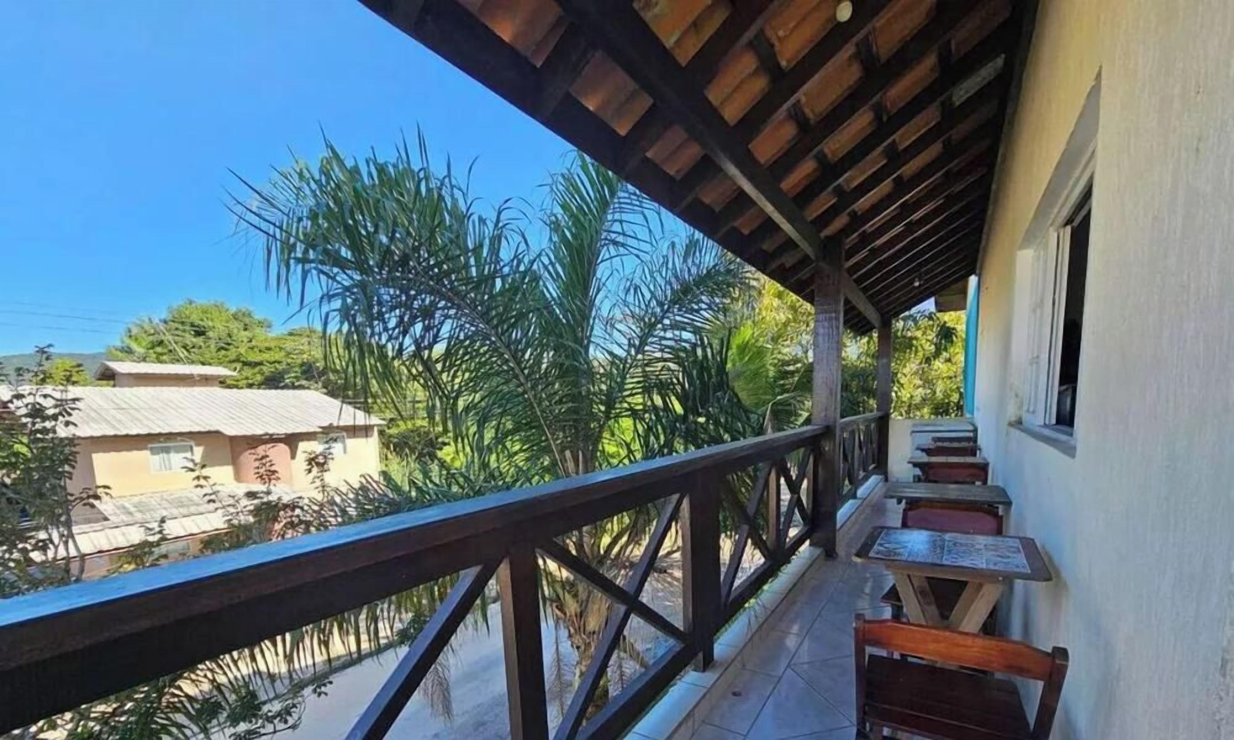 Un balcón con barandilla de madera, una mesa y sillas, con vistas a una zona residencial con árboles y edificios.
