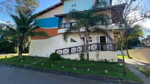A two-story building with a balcony, surrounded by greenery and palm trees. - Pousada Meraki Beach (Caraguatatuba)