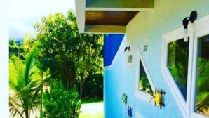 A pathway leading to a building with multiple windows and a blue exterior. - Pousada Meraki Beach (Caraguatatuba)