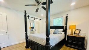 A four-poster bed with a headboard, a bedside table with a lamp, and a framed sign on the wall. - Lakefront Home w/ Dock on Old Hickory Lake (Gallatin)