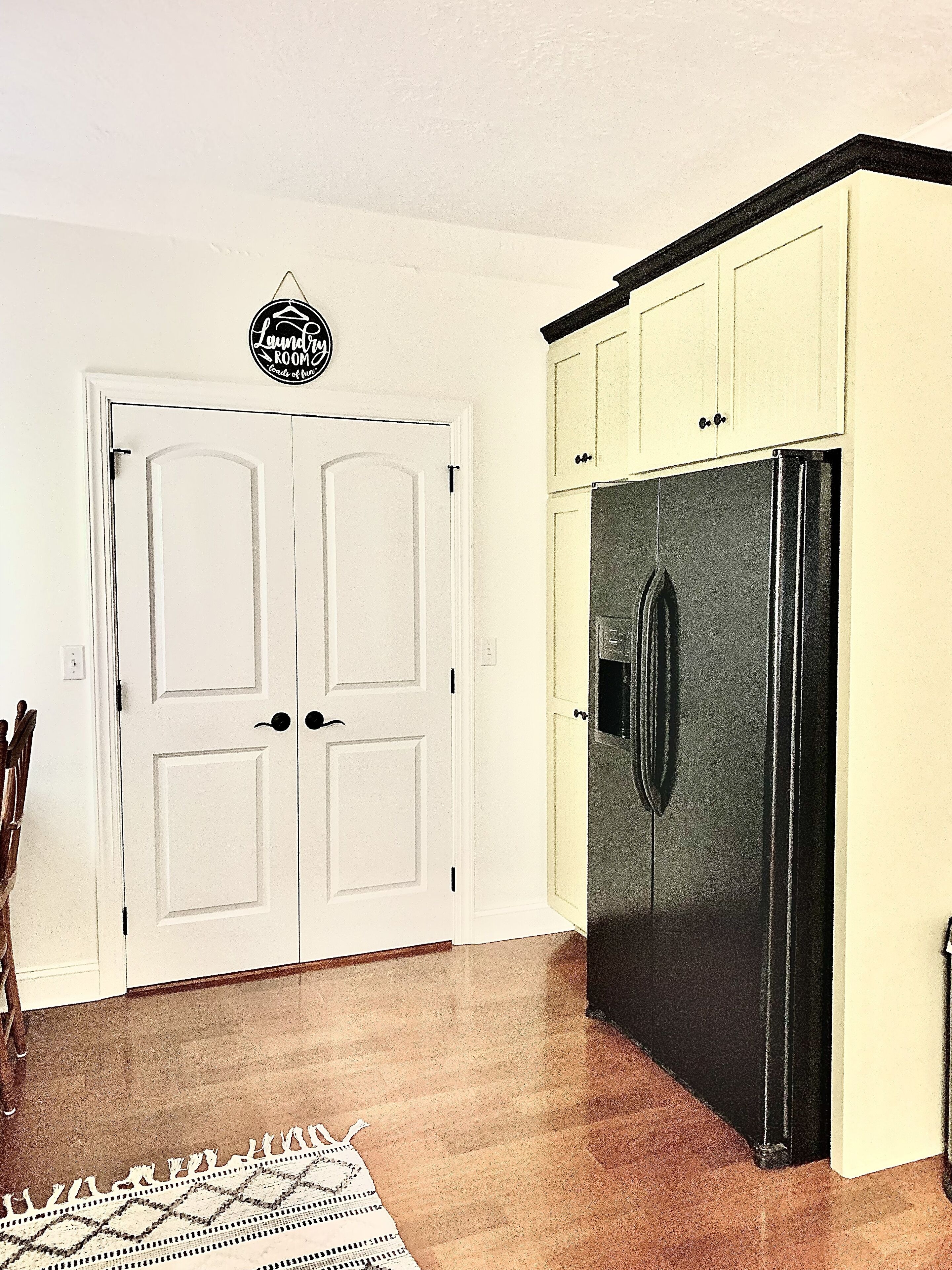A kitchen with a double door, a refrigerator, and a patterned rug.