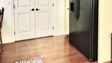 A kitchen with a double door, a refrigerator, and a patterned rug.