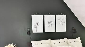 Une chambre à coucher comprenant un lit, des tables de chevet, une commode et des œuvres d’art murales.