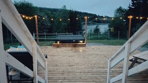 Um deck de madeira com churrasqueira e luzes de cordão.