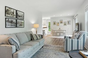 Un salon comprenant un canapé, un fauteuil et un coin repas avec une table et des chaises.