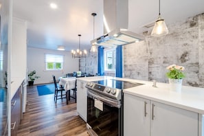 A modern kitchen with a central island, stainless steel appliances, and pendant lighting.