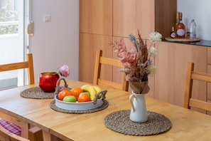 A wooden dining table with a fruit bowl, a vase with dried flowers, and a red pot. - Modern apt with terrace 4 min walk to the beach (Split)