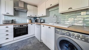 A compact kitchen with a built-in oven, dishwasher, and washing machine. - A cozy cottage on the North Norfolk coast (Brancaster Saithe)
