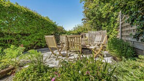 A garden patio with wooden furniture and a brick floor. - A cozy cottage on the North Norfolk coast (Brancaster Saithe)
