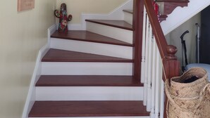 Una escalera de madera con barandas blancas y una cesta colgando de un lado.