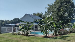 Una propiedad residencial con piscina, patio cercado y una casa de techo azul.