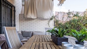 A wooden table with chairs, a hanging curtain, potted plants, and a metal gate. - Vila del Far by Interhome (St Carles de la Ràpita)