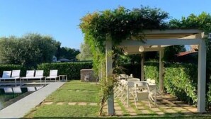 Ein Garten mit Pool, Liegestühlen und einer Pergola.