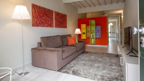 Ein modernes Wohnzimmer mit einem braunen Sofa, einer Stehlampe und farbenfroher abstrakter Kunst an der Wand.