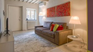 Ein modernes Wohnzimmer mit einer braunen Couch, einem transparenten Glastisch und einer Heizung.