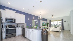 A modern kitchen with white cabinets, stainless steel appliances, and pendant lighting.