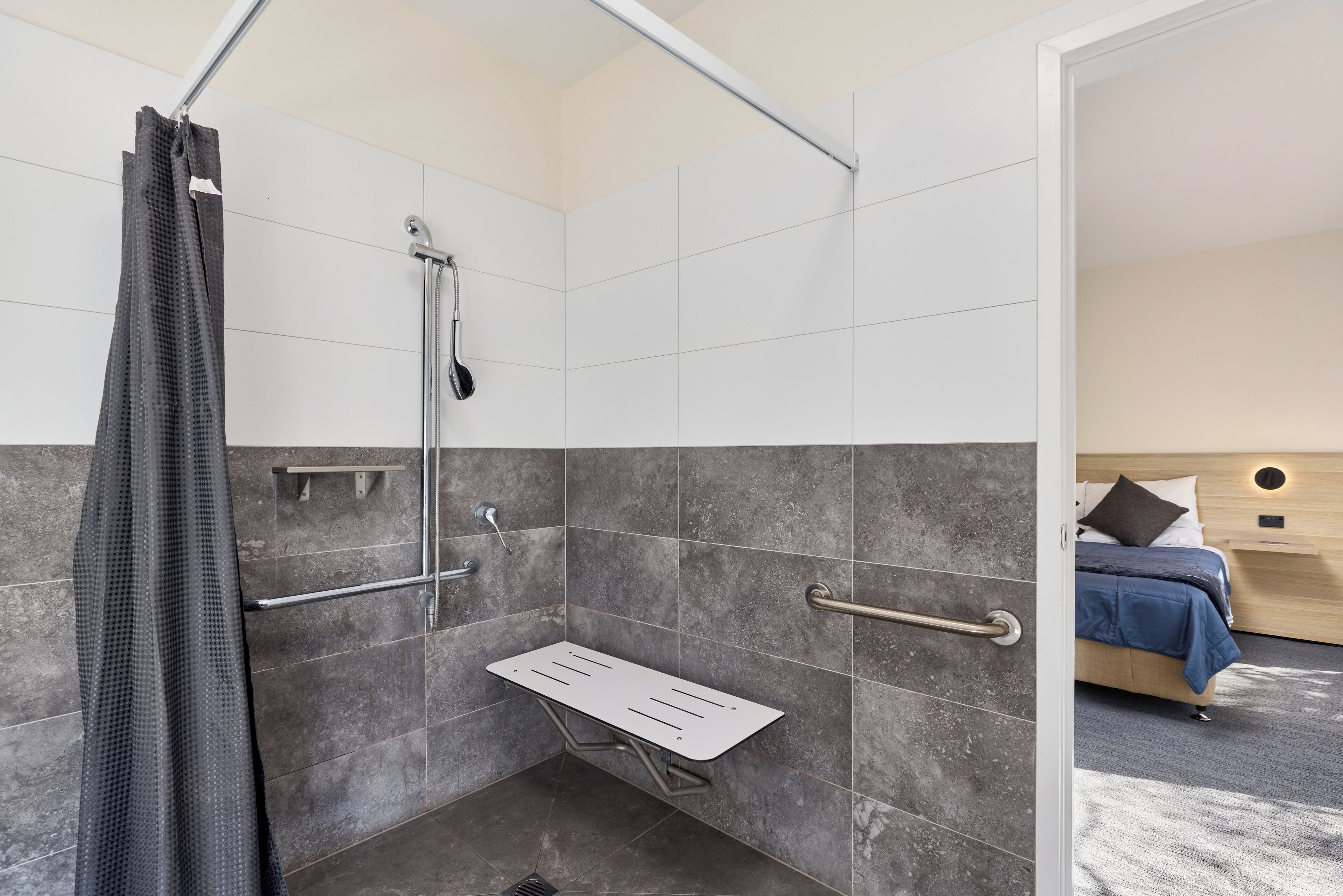 A modern bathroom with a shower, grab bars, and a shower seat.