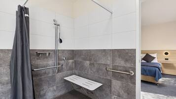A modern bathroom with a shower, grab bars, and a shower seat.