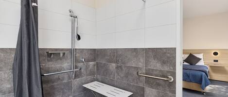 A modern bathroom with a shower, grab bars, and a shower seat.