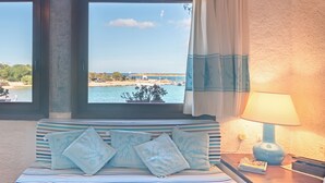 Un lit avec une literie à rayures, une lampe et une vue sur la mer.
