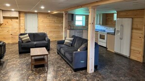Un espace de vie compact comprenant un coin cuisine, deux canapés, une petite table et un réfrigérateur.