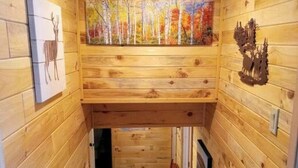 Un intérieur en bois avec un escalier, un tableau représentant des arbres et une œuvre d’art représentant un cerf.