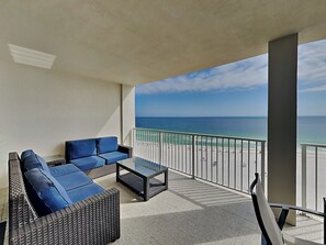 Un balcon avec vue sur la plage, aménagé avec un canapé et une table basse.