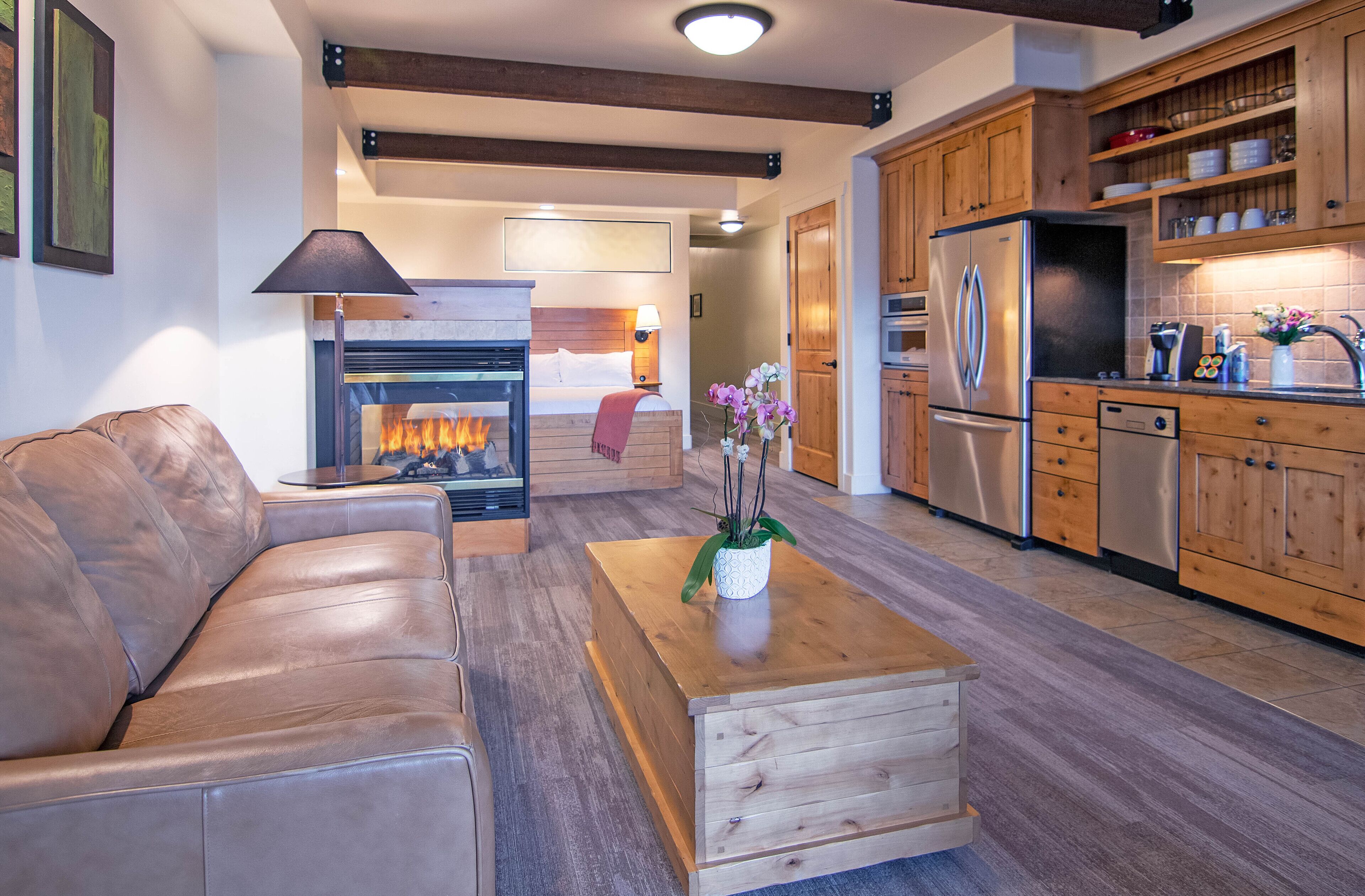 Een moderne woonkamer met een leren bank, een houten salontafel en een open haard.
