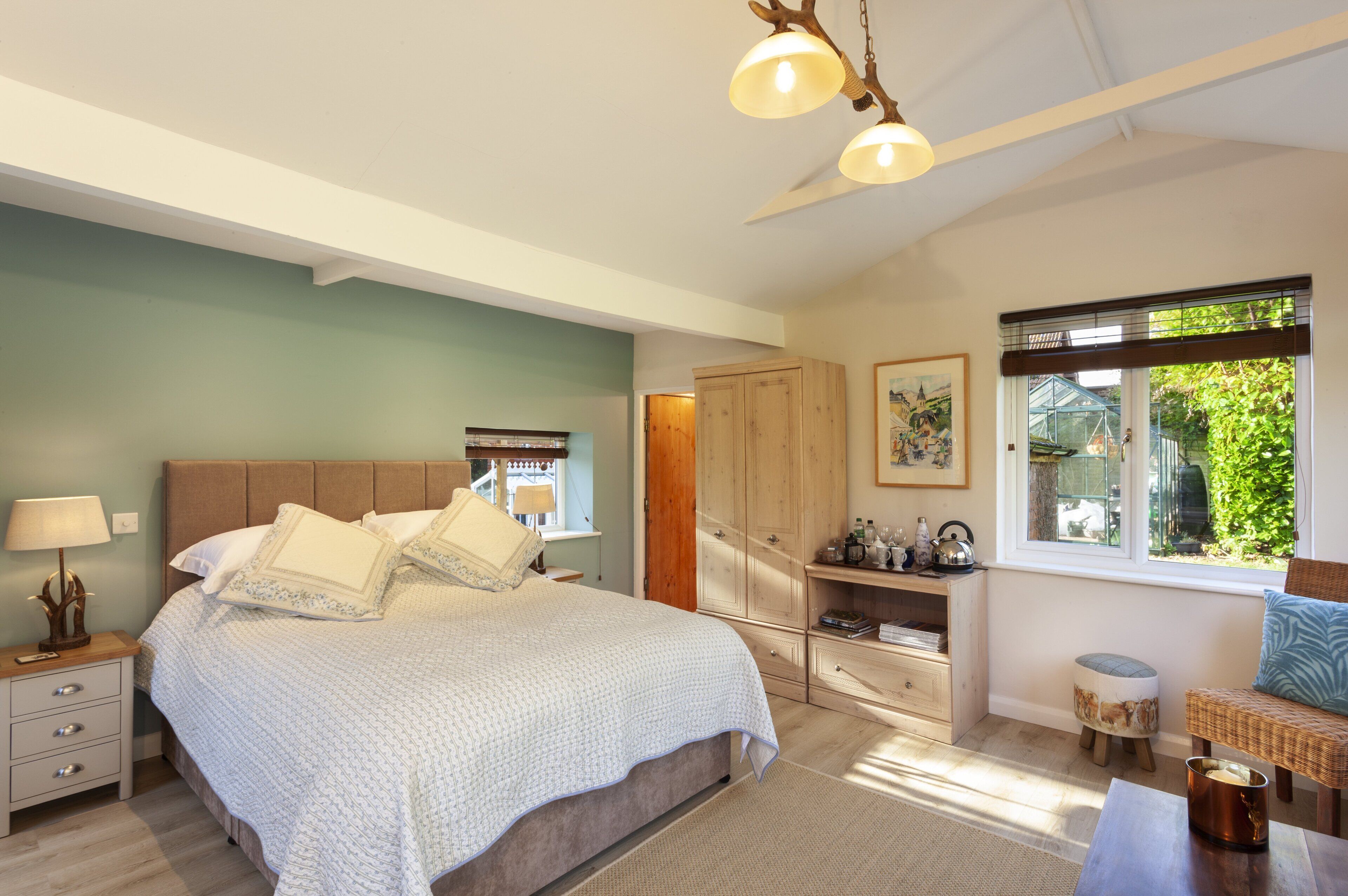 A bedroom with a large bed, bedside tables, a wardrobe, a window with a view, and a ceiling fan.