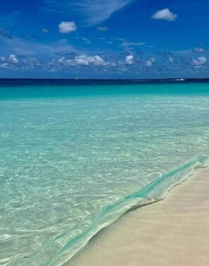 A beach with clear turquoise water and a sandy shore.