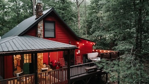 A cabin with a porch, outdoor seating, and string lights.