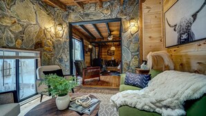 Un interior rústico con paredes de piedra, vigas de madera, una zona de estar acogedora y un comedor.