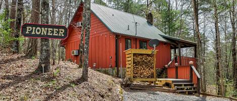 A red cabin with a sign reading "PIONEER" in a forested area.