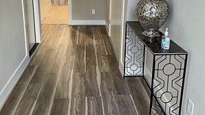 A hallway with wooden flooring, a decorative vase on a console table, and a door leading to another room. - Upscale brand new beautiful 3bedroom, 2 story home! (Houston)