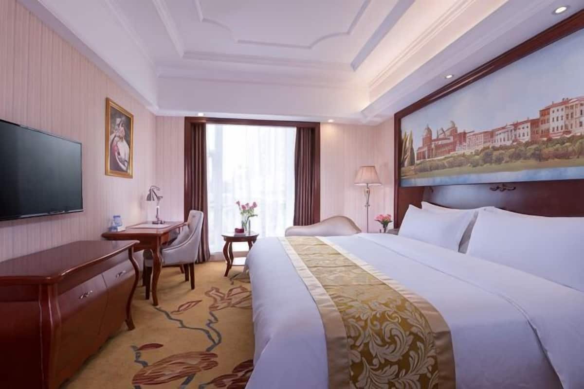 Une chambre dâhĂŽtel avec un lit, un bureau, une tĂ©lĂ©vision et un tableau au mur.