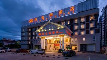 A hotel with a prominent entrance, multiple floors, and a parking lot.