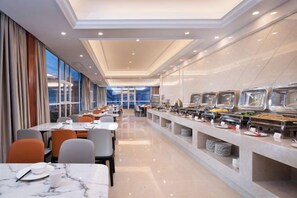 A hotel dining area with long tables, chairs, and a buffet counter. - Vienna Hotel (Gaozhou Chengdong Passenger Station) (Gaozhou)