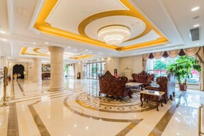 A hotel lobby with a central seating area, a chandelier, and a large window with curtains. - Vienna Hotel (Gaozhou Chengdong Passenger Station) (Gaozhou)