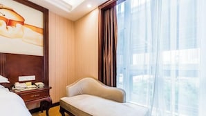 A hotel room with a bed, a sofa, a desk with a lamp, and a large window with curtains. - Vienna Hotel (Gaozhou Chengdong Passenger Station) (Gaozhou)
