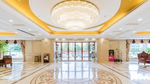 A spacious lobby with a large chandelier, a central decorative floor pattern, and a view of the outside through the entrance doors. - Vienna Hotel (Gaozhou Chengdong Passenger Station) (Gaozhou)