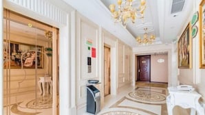 A hotel hallway with a patterned floor, a chandelier, and a door with a glass panel. - Vienna Hotel (Gaozhou Chengdong Passenger Station) (Gaozhou)