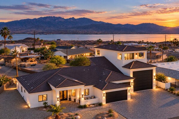 Zona residencial con casas modernas, un camino de entrada y vistas a montañas y un cuerpo de agua.