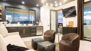 Un salon moderne comprenant un canapé, deux fauteuils, une table basse et un téléviseur.