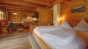 A wooden cabin-style room with a bed, a desk, and a dining area. - Vacation apartment Falkenstein for 2 to 3 persons with balcony, 40 sqm, n. k. (Inzell)