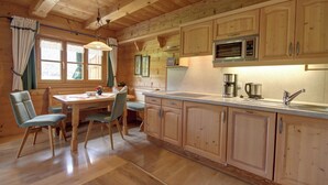 A wooden cabin-style kitchen with a dining table and chairs, wooden cabinets, and a built-in microwave. - Vacation apartment Falkenstein for 2 to 3 persons with balcony, 40 sqm, n. k. (Inzell)
